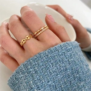 Detailed view of three gold-plated rings with chain links and sparkling zircon stones
