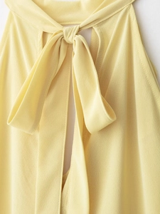 Detail of the chic pale yellow chiffon blouse showing the neck tie bow design clearly