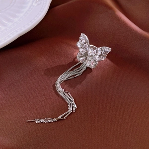 Detailed macro of a silver zircon butterfly tassel clip earring on elegant brown silk