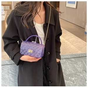 Detailed view of purple transparent jelly bag with gold chain and quilted pattern