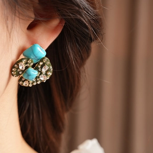 Detailed close-up of vintage irregular earrings with turquoise stones and sparkling rhinestones