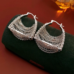 Macro shot of silver tassel chain earrings with micro-zircon stones on green velvet