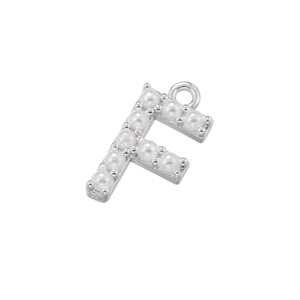 Close-up of silver letter F pendant featuring white pearl embellishments on metal surface