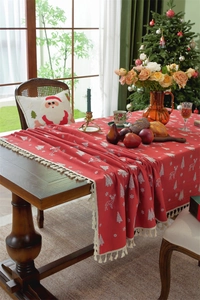 Detail of red Christmas tablecloth featuring white reindeer motifs and beige tassel fringe