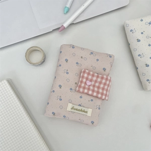Detailed view of a pink floral fabric book cover with heart button and Sozakka brand label