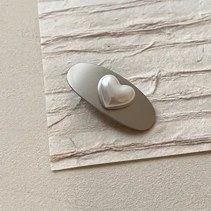 Detailed view of an oval matte grey metal hair clip with a pearl heart ornament