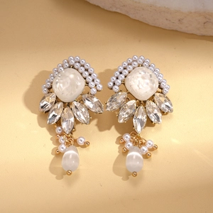 Macro detail of geometric drop earrings featuring white pearls and marquise cut crystals