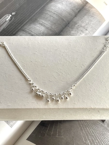 Flat lay of a 925 sterling silver beaded bracelet on a minimalist textured paper box