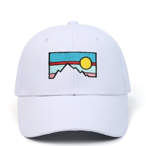 Detailed close-up of scenic sunset embroidery on a white cotton baseball cap