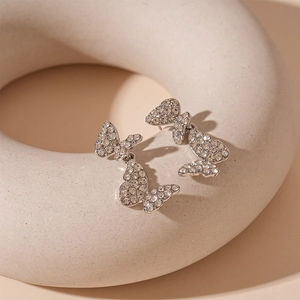 Macro shot of silver butterfly earrings with sparkling crystals on minimalist ceramic base