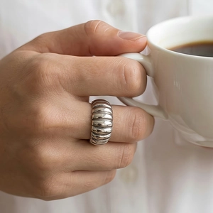 Detailed view of silver textured band ring with horizontal grooves on hand