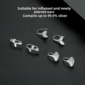 Close-up of S999 silver ginkgo leaf earrings on a textured grey luxury background