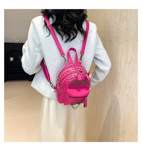 Close-up of a pink mini backpack with punk metal studs and chain zippers on model