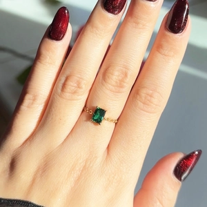 Detail of 18K gold plated chain ring featuring a green emerald cut zircon on finger