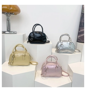 Mini bowling handbags in four colors displayed on geometric pedestals with long straps