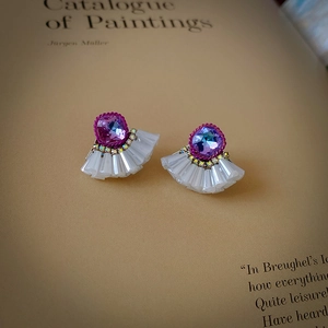 Detail of vintage fan-shaped earrings with purple crystals and white pleated textures