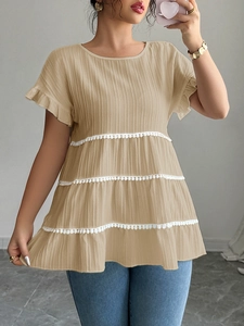Detail of khaki short sleeve blouse featuring multi-layered ruffles and white pompom trim