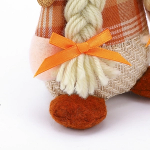 Detailed close-up of orange plaid fabric and woven yarn braids on the festive doll