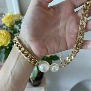 Detail of chunky gold chain necklace featuring faux pearls and adjustable clasp link