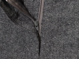 Détail du tissu en tweed gris foncé et de la fermeture éclair en métal sur la veste