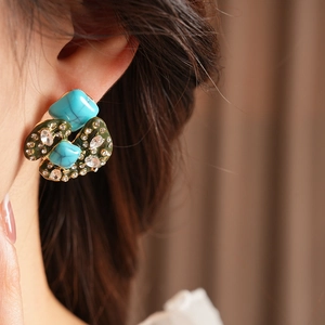 Detail of vintage bohemian earrings with turquoise stones and crystals on a model