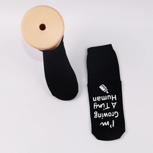 Detail of black ankle socks with white I'm Growing A Tiny Human print and bottle icon