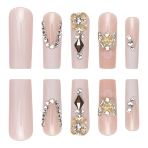 Long coffin press-on nails in nude pink with rhinestones and gold butterfly charms