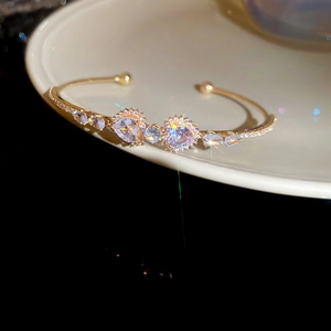 Macro view of gold heart-shaped zircon open bangle with sparkling stone details