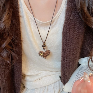 Close-up of leopard print heart pendant with yellow crystal on brown woven necklace
