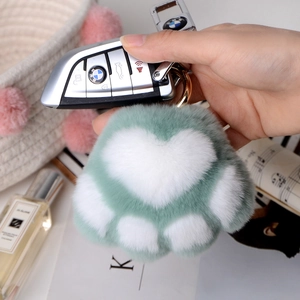 Close-up of green and white plush cat paw keychain with premium gold metal clasp