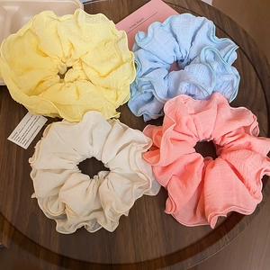 Detailed macro view of four pastel ruffled scrunchies on a wooden tray