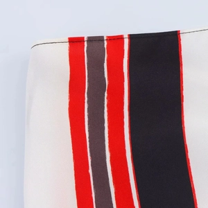 Close-up detail of red, black, and white striped twill fabric with neat black stitching