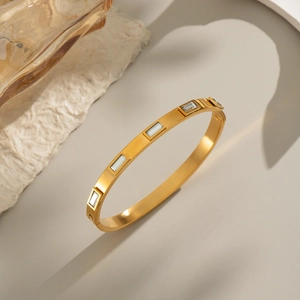 Gros plan d'un bracelet jonc plaqué or 18k orné de zircons rectangulaires et d'un fermoir