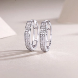 Close-up of silver hoop earrings with double row pave-set moissanite on beige background