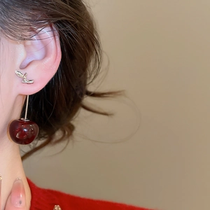 Dettaglio di un orecchino vintage a ciliegia in resina rossa con foglie d'argento