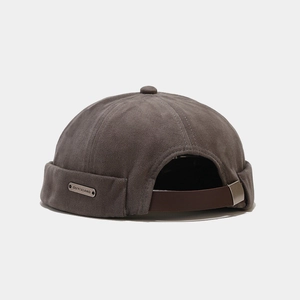 Détail du bonnet docker avec lanière en cuir, boucle métal et plaque logo métallique