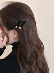 Dettaglio di un fermaglio per capelli in velluto con cuore dorato su capelli mossi