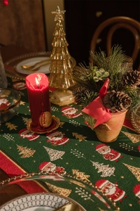 Detailed view of green woven Christmas table runner with Santa Claus and tree patterns