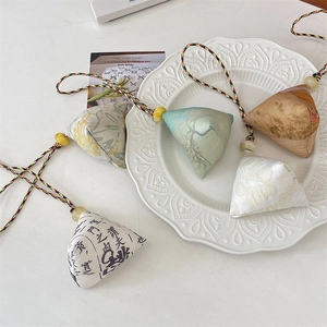 Detailed view of handmade pyramid zongzi fabric charms with floral patterns and tassels