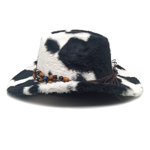 Détail d'un chapeau de cowboy en peluche à motif vache avec perles en bois et cordon tressé