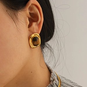 Close-up of vintage gold stainless steel earring with tiger eye stone on model ear