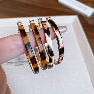 Detail of leopard print hoop earrings featuring textured patterns and C-shape design