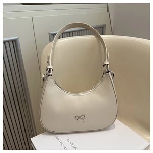 Detailed macro view of cream crescent bag featuring silver bow hardware and adjustable strap