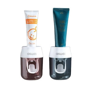 Automatic wall-mounted toothpaste dispensers in brown and green colors on white background