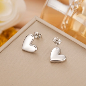 Detailed close-up of polished silver heart stud earrings resting on a luxury jewelry box