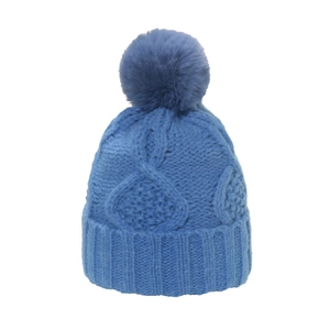 Detaillierte Strickstruktur und weicher blauer Pompon oben auf dieser Wintermütze