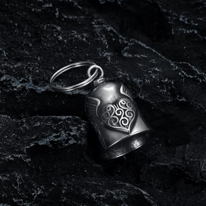 Macro shot of stainless steel motorcycle bell featuring heart wings on dark stone