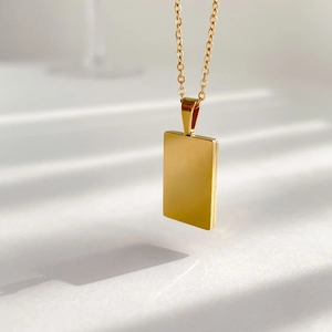 Close-up of a rectangular gold sun pendant necklace with polished mirror surface