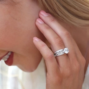Luxurious four-prong silver ring with large round solitaire and pave-set band on finger