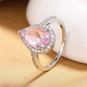 Macro shot of silver ring featuring pear-shaped pink gemstone and small accent diamonds